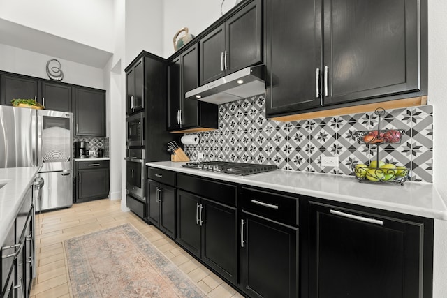 kitchen with appliances with stainless steel finishes, light hardwood / wood-style flooring, and tasteful backsplash