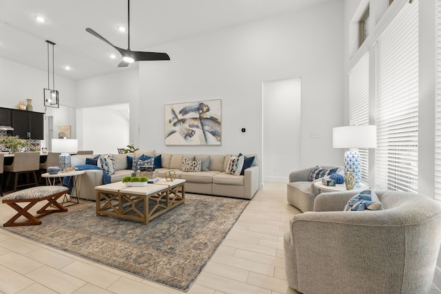 living room with ceiling fan, light hardwood / wood-style flooring, and a towering ceiling