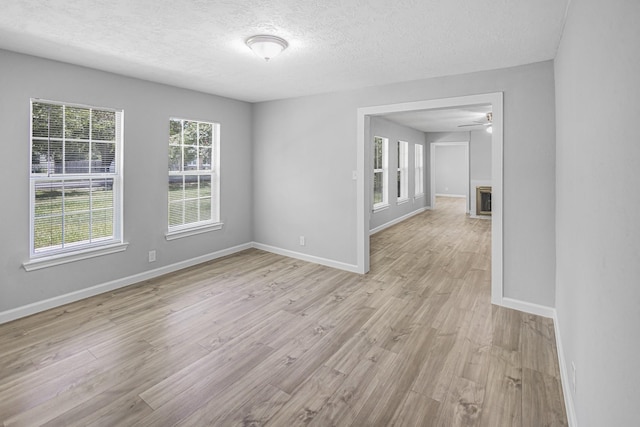 spare room with light hardwood / wood-style floors, a textured ceiling, ceiling fan, and a fireplace