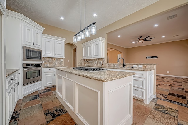 kitchen featuring appliances with stainless steel finishes, backsplash, a center island, kitchen peninsula, and ceiling fan