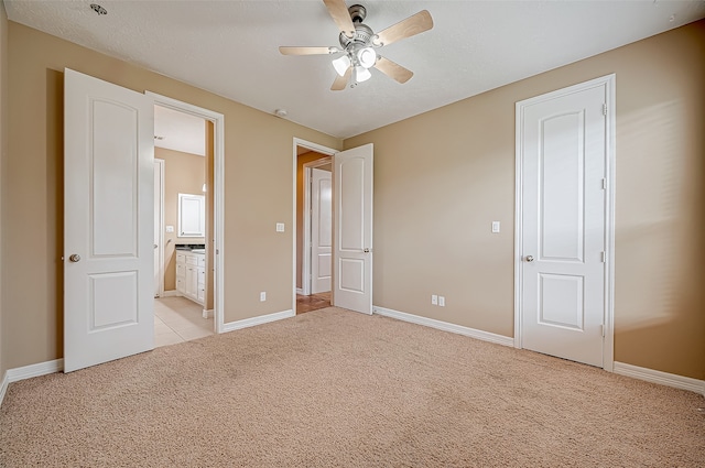 unfurnished bedroom with light colored carpet, connected bathroom, and ceiling fan