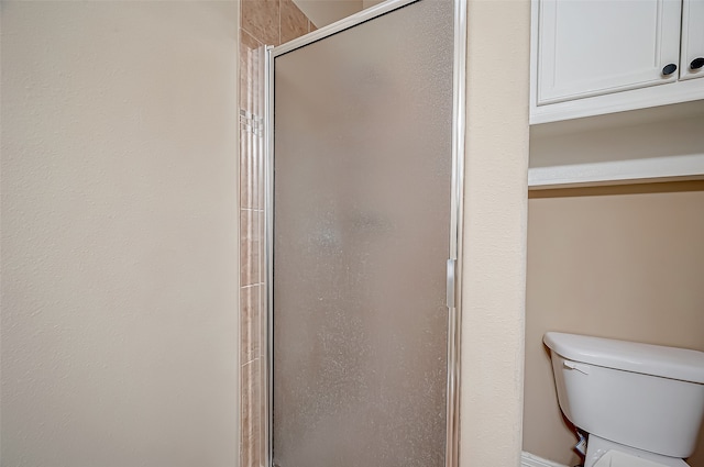 bathroom featuring toilet and a shower with shower door