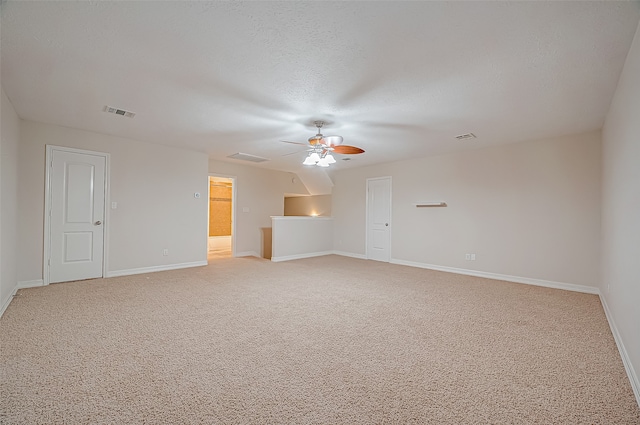 spare room with ceiling fan, a textured ceiling, and light colored carpet