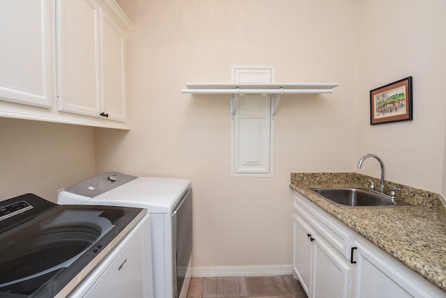 clothes washing area featuring cabinets, light hardwood / wood-style flooring, sink, and washing machine and dryer