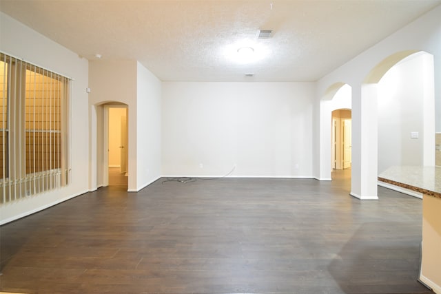 empty room with a textured ceiling and dark hardwood / wood-style flooring