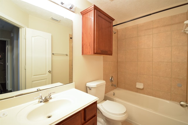 full bathroom with a textured ceiling, tiled shower / bath, vanity, and toilet