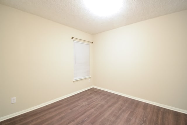 spare room featuring a textured ceiling and dark wood-type flooring