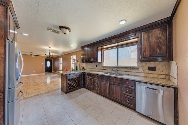 kitchen with pendant lighting, sink, kitchen peninsula, stainless steel appliances, and light stone countertops