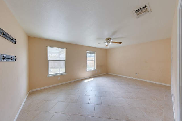 empty room with ceiling fan and light tile patterned floors