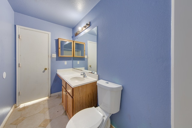 bathroom featuring a textured ceiling, vanity, toilet, and tile patterned floors