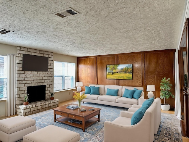 living room featuring wood walls, a fireplace, and plenty of natural light