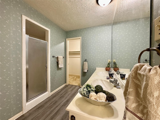 bathroom featuring vanity, a textured ceiling, hardwood / wood-style flooring, and a shower with door