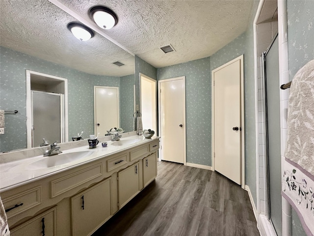 bathroom with a textured ceiling, vanity, wood-type flooring, and an enclosed shower