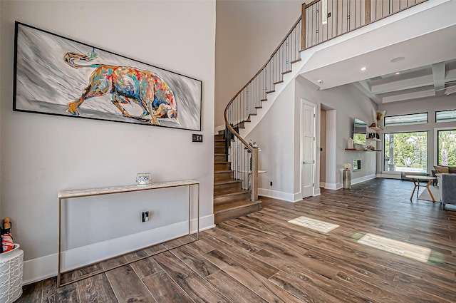 foyer featuring hardwood / wood-style floors, beamed ceiling, and a high ceiling