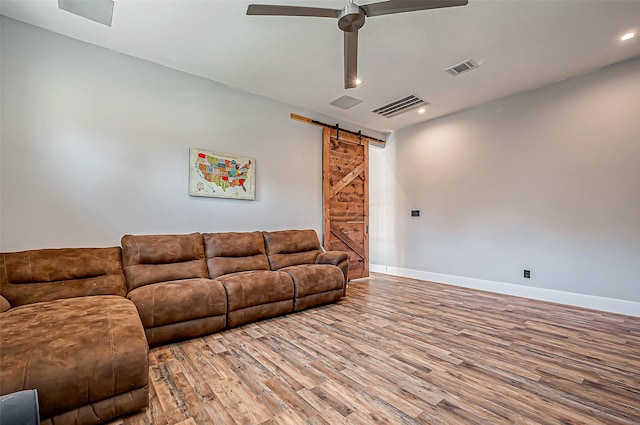 living room with hardwood / wood-style flooring, a barn door, and ceiling fan