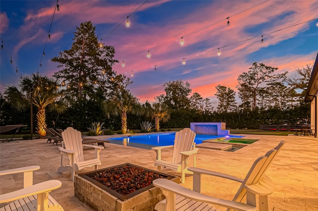 pool at dusk featuring a patio area, an in ground hot tub, and an outdoor fire pit