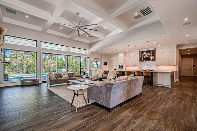 living room featuring dark hardwood / wood-style flooring, a towering ceiling, coffered ceiling, and beamed ceiling