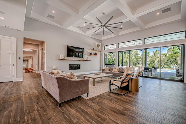 living room with coffered ceiling, dark hardwood / wood-style floors, beamed ceiling, and a high ceiling