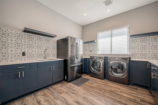 laundry room with cabinets, sink, washer and dryer, and light wood-type flooring