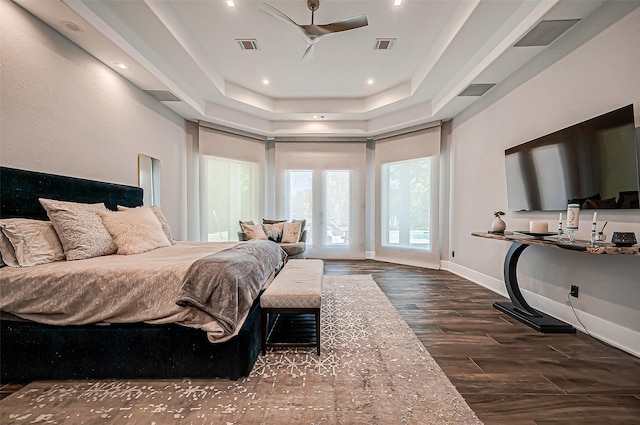 bedroom featuring dark hardwood / wood-style flooring, access to exterior, and a tray ceiling