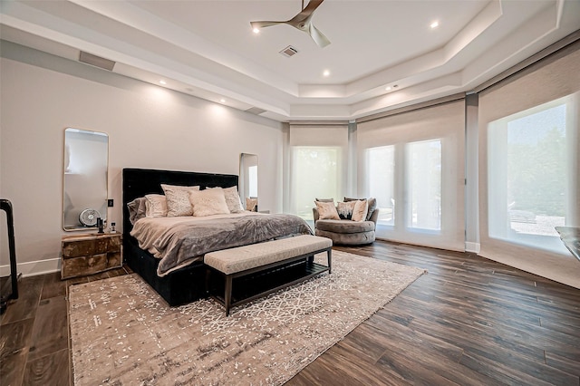 bedroom featuring ceiling fan, a tray ceiling, dark hardwood / wood-style floors, and access to exterior