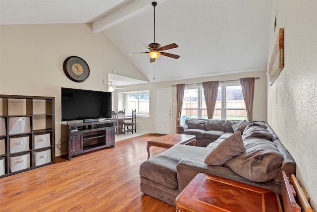 living room featuring beam ceiling, ceiling fan, light hardwood / wood-style flooring, and high vaulted ceiling