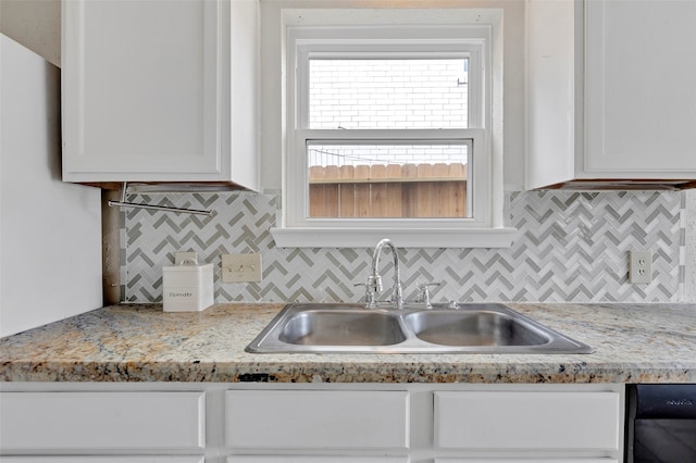 kitchen with decorative backsplash, white cabinetry, light stone countertops, and sink