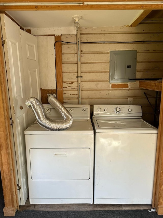 laundry area with wood walls, electric panel, and washing machine and clothes dryer