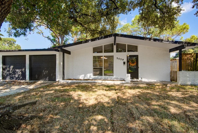 view of front of home with a garage, fence, and brick siding