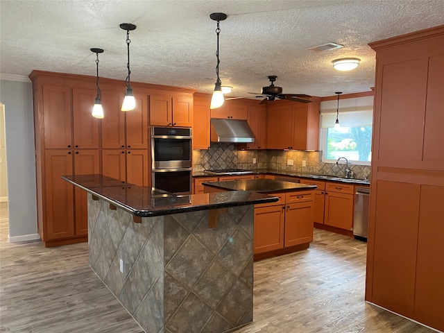 kitchen with hanging light fixtures, a center island, light hardwood / wood-style flooring, and sink