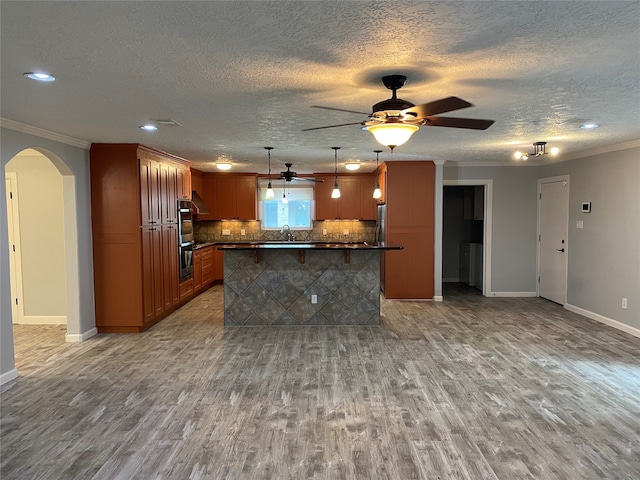 kitchen featuring ornamental molding, light hardwood / wood-style floors, decorative light fixtures, and a textured ceiling