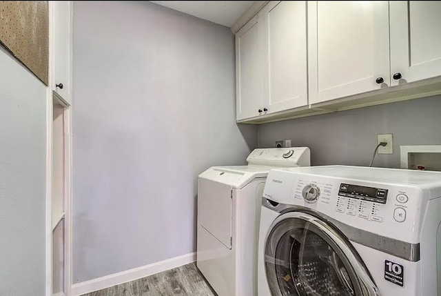 washroom featuring light hardwood / wood-style floors, separate washer and dryer, and cabinets