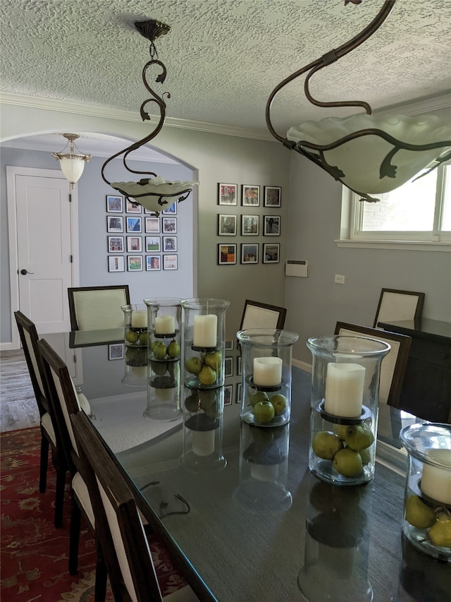 dining area with a textured ceiling, ornamental molding, and hardwood / wood-style flooring