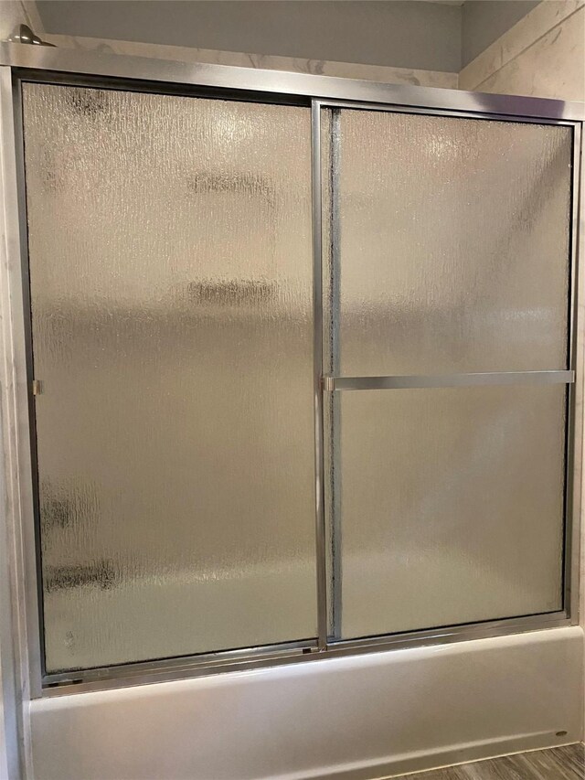 9614 Greenwillow St, Houston, TX 77096 - bathroom with wood finished floors and bath / shower combo with glass door