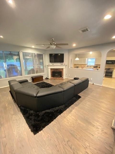 19603 Huckleberry Branch Ct, Spring, TX 77388 - living area featuring a ceiling fan, a brick fireplace, wood finished floors, baseboards, and arched walkways