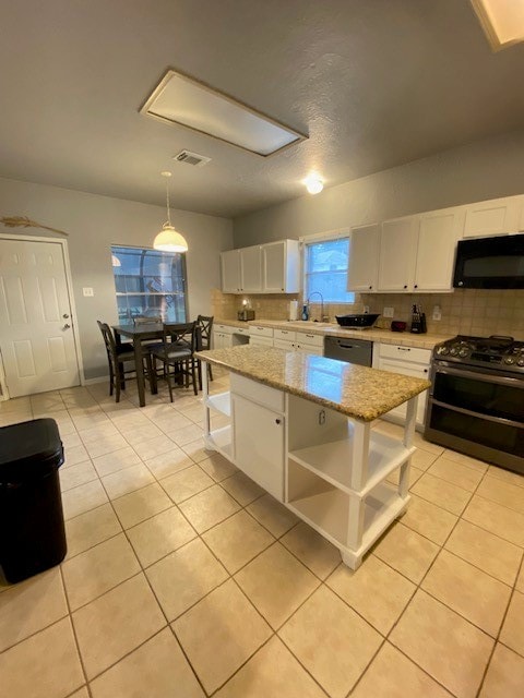 kitchen featuring white cabinets, sink, decorative light fixtures, black appliances, and a center island