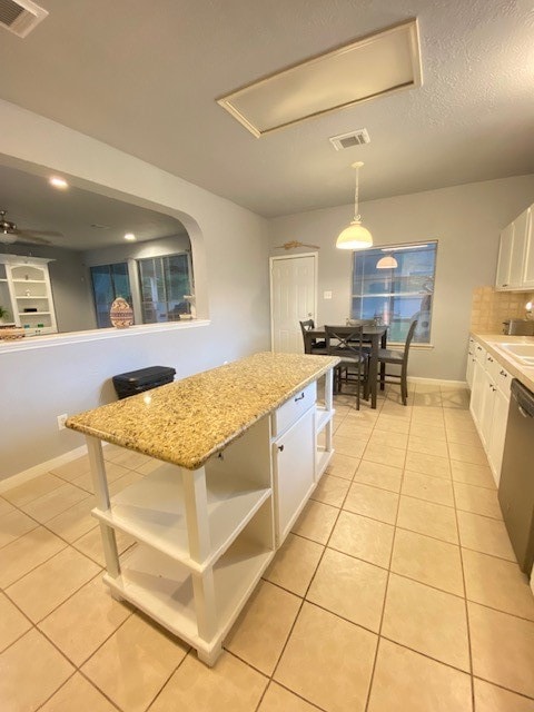 kitchen with decorative light fixtures, light stone countertops, light tile patterned floors, and white cabinets