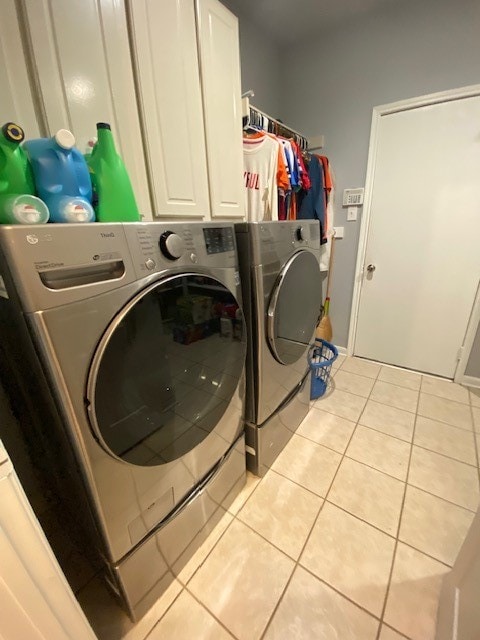 laundry room with cabinets, light tile patterned flooring, and washer and dryer