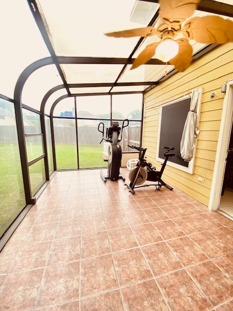 exercise area with a healthy amount of sunlight, wood walls, ceiling fan, and tile patterned floors