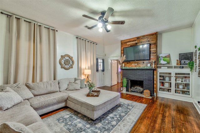 living room featuring a textured ceiling, a fireplace, ceiling fan, and dark wood-type flooring