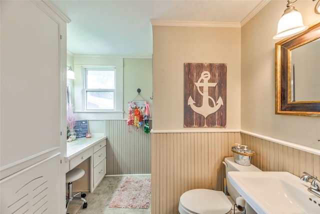 bathroom featuring wood walls, crown molding, vanity, and toilet