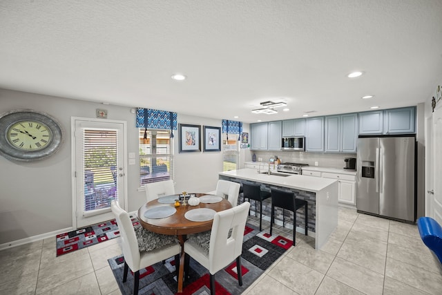 tiled dining room with a textured ceiling and sink