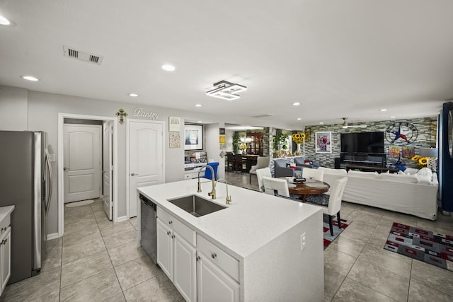 kitchen featuring sink, white cabinets, stainless steel appliances, a center island with sink, and light tile patterned floors