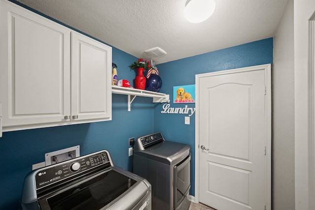 clothes washing area featuring cabinets, a textured ceiling, and separate washer and dryer