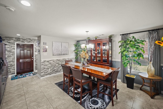 tiled dining area with a textured ceiling and an inviting chandelier