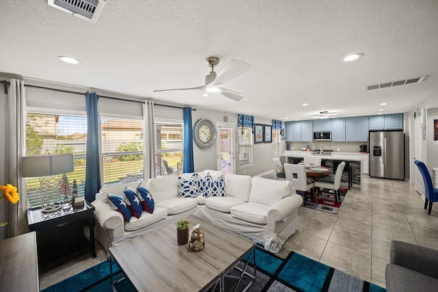 living room with a textured ceiling, light tile patterned floors, and ceiling fan