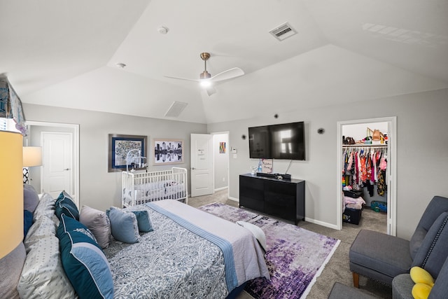 bedroom featuring ceiling fan, lofted ceiling, a walk in closet, a closet, and light carpet