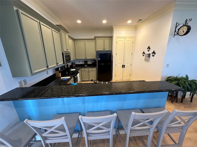 kitchen featuring ornamental molding, kitchen peninsula, gray cabinets, stainless steel appliances, and a kitchen bar