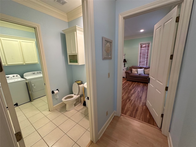 bathroom with hardwood / wood-style flooring, washer and dryer, crown molding, and toilet