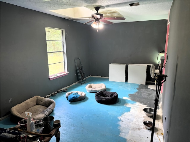 miscellaneous room with ceiling fan and a textured ceiling